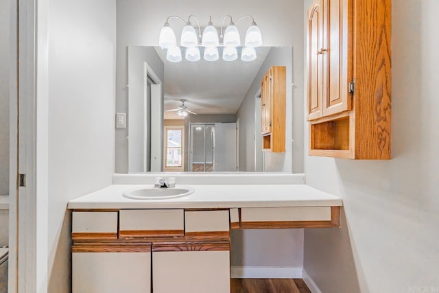 bathroom with toilet, wood finished floors, a ceiling fan, vanity, and baseboards