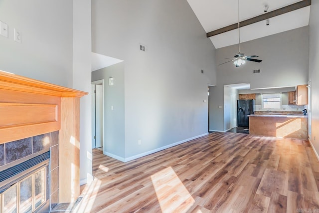 unfurnished living room with baseboards, visible vents, a ceiling fan, light wood-style floors, and a fireplace