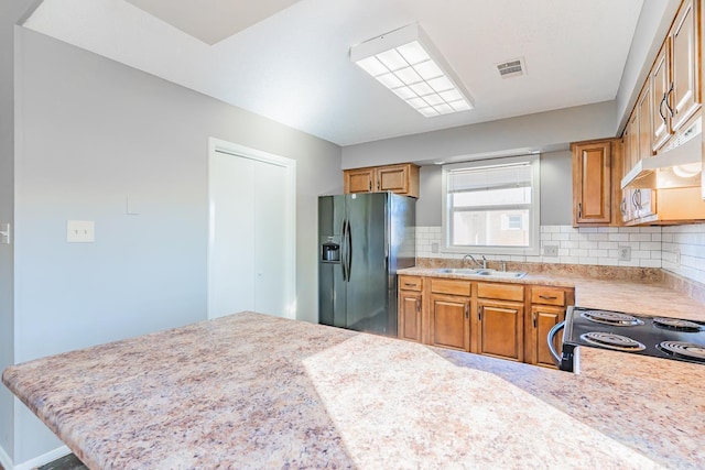 kitchen featuring tasteful backsplash, visible vents, light countertops, black fridge, and a sink