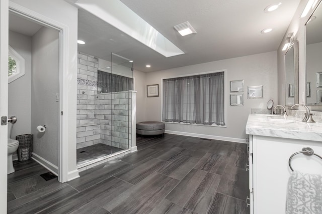 full bath featuring a walk in shower, vanity, toilet, and baseboards
