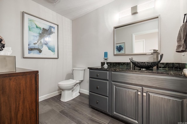 bathroom featuring toilet, wood finished floors, vanity, and baseboards
