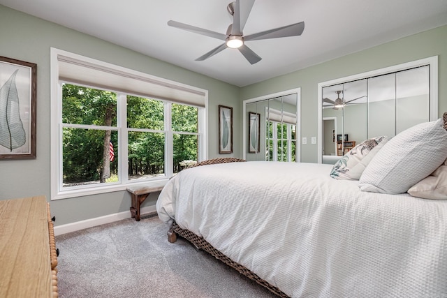carpeted bedroom with a ceiling fan, baseboards, and two closets