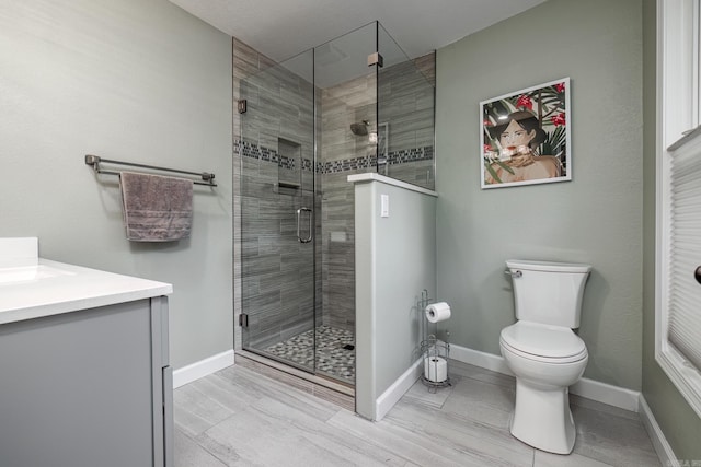 full bathroom with a stall shower, vanity, toilet, and baseboards