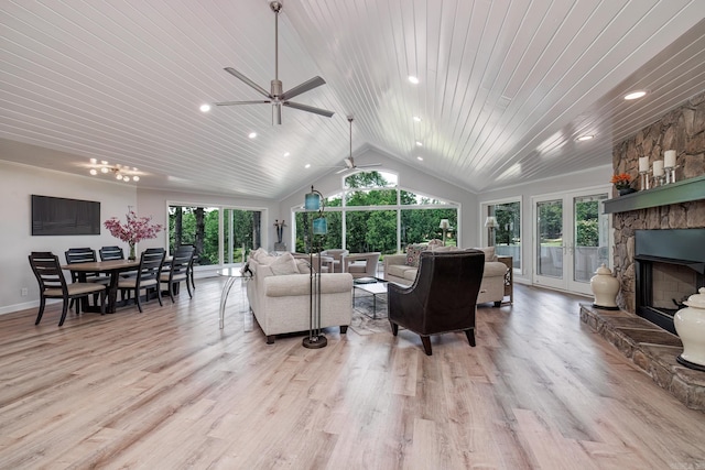 living room with vaulted ceiling, a stone fireplace, plenty of natural light, and wood finished floors