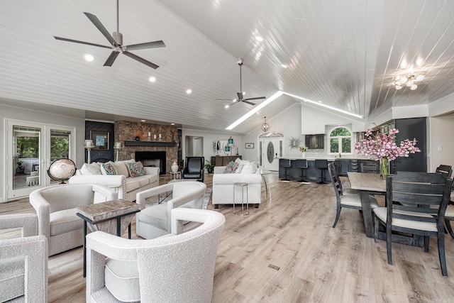 living area featuring vaulted ceiling, light wood-type flooring, a fireplace, and wood ceiling