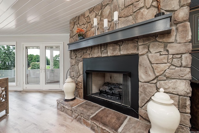 room details featuring french doors, crown molding, a stone fireplace, and wood finished floors