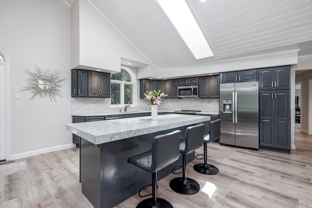 kitchen with light wood-style flooring, stainless steel appliances, a breakfast bar, a sink, and light countertops
