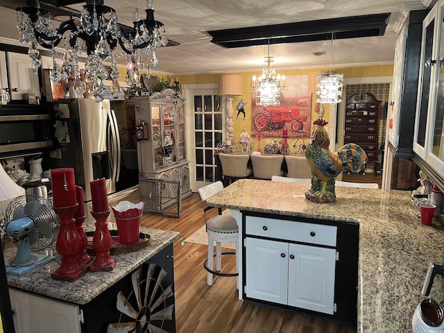 kitchen with dark wood-style floors, a peninsula, stainless steel appliances, a chandelier, and pendant lighting