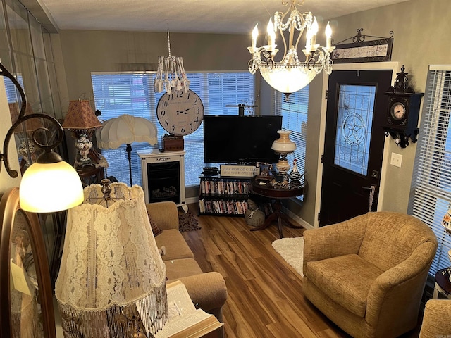 living area with a notable chandelier, baseboards, and wood finished floors