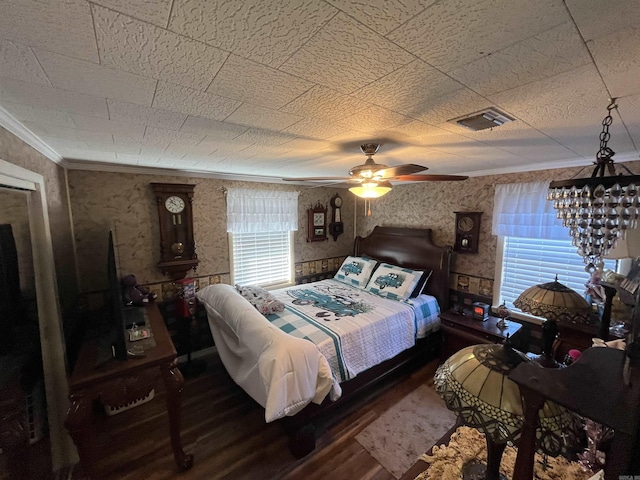 bedroom featuring wood finished floors, visible vents, ornamental molding, multiple windows, and wallpapered walls