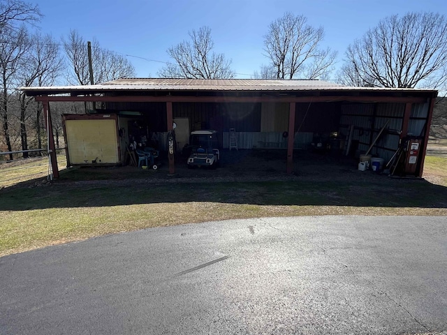 view of parking / parking lot featuring fence and a pole building