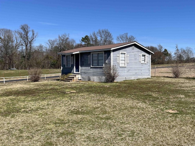 view of front facade featuring entry steps, metal roof, fence, and a front lawn