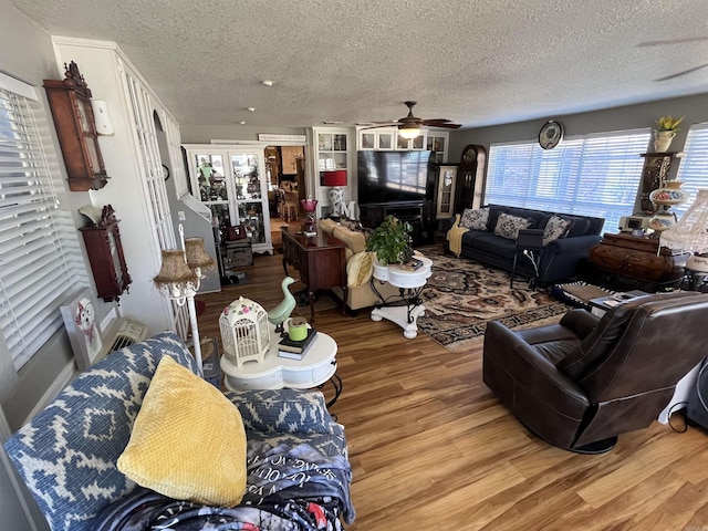 living room with a textured ceiling, a ceiling fan, and wood finished floors