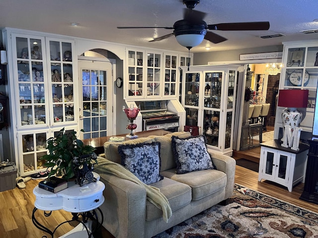 living area featuring a ceiling fan, visible vents, arched walkways, and wood finished floors