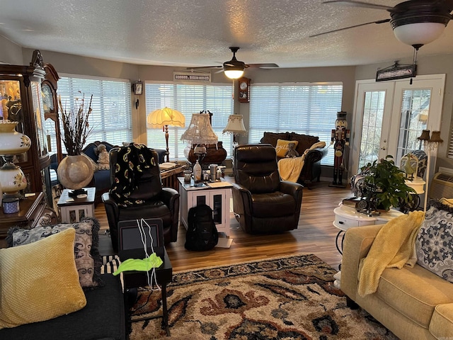 living area with ceiling fan, a textured ceiling, and wood finished floors