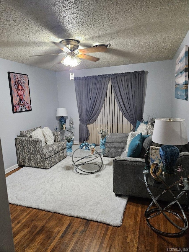 living area with a textured ceiling, a ceiling fan, and wood finished floors