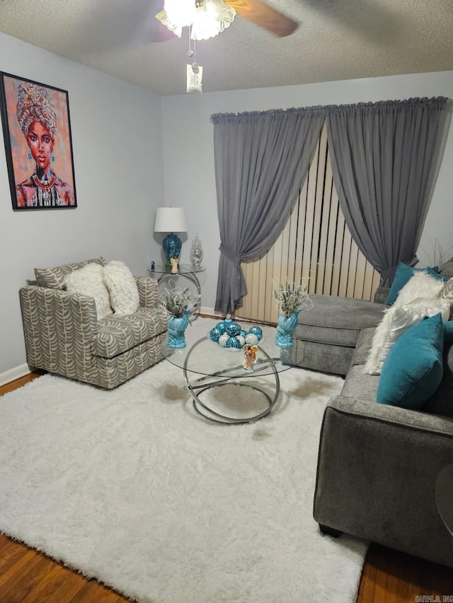 living area with baseboards, a textured ceiling, a ceiling fan, and wood finished floors