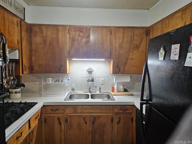 kitchen with black appliances, a sink, light countertops, and decorative backsplash