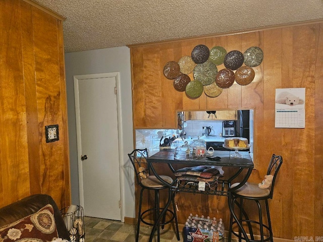 kitchen with wooden walls, brown cabinets, and a textured ceiling