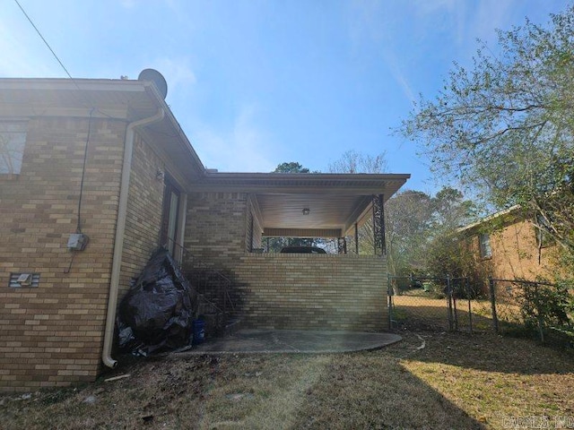 view of side of home with a gate, fence, and brick siding