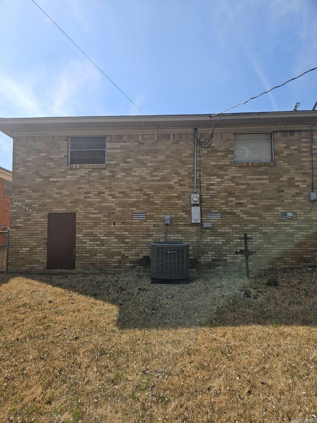 view of side of home with brick siding, a lawn, and central air condition unit