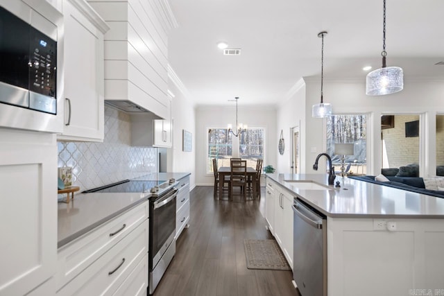 kitchen with crown molding, stainless steel appliances, visible vents, decorative backsplash, and a sink