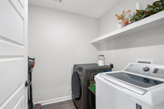 laundry room with laundry area, washer and clothes dryer, dark wood finished floors, and baseboards