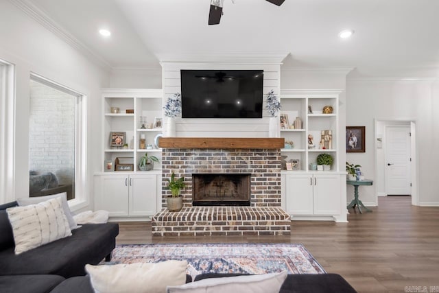 living room featuring baseboards, a ceiling fan, wood finished floors, crown molding, and a fireplace