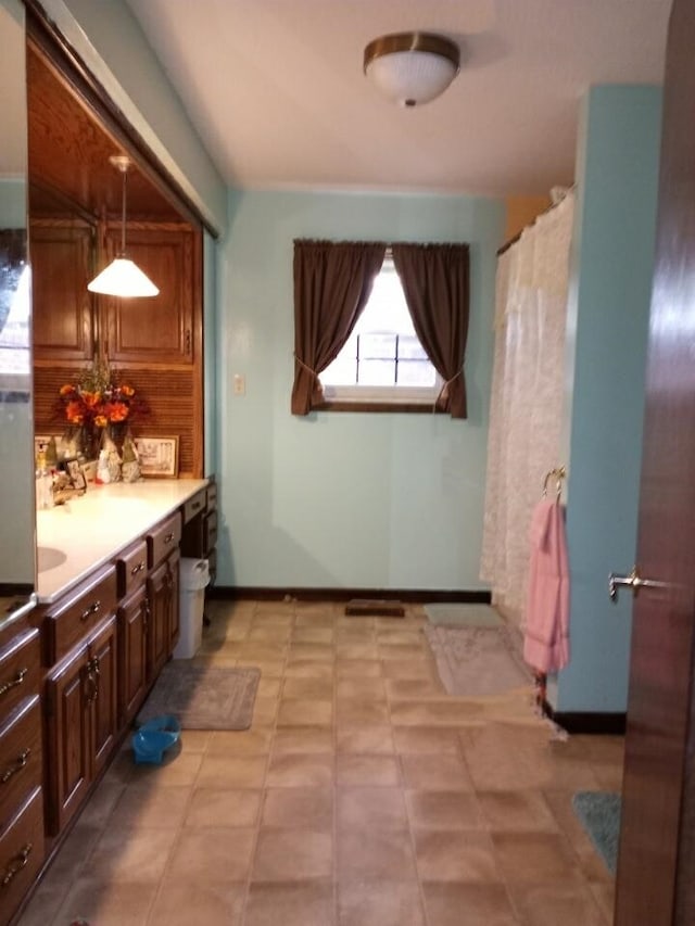 full bath featuring curtained shower, baseboards, and vanity