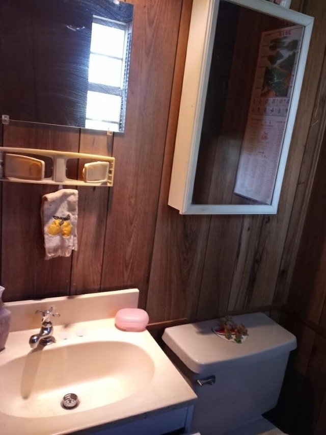 bathroom with vanity, toilet, and wooden walls