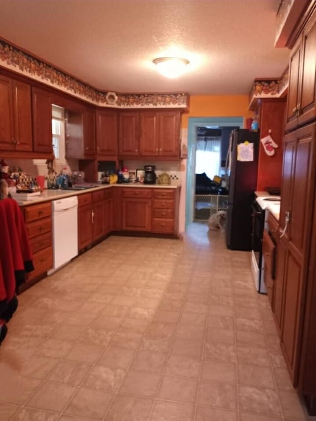 kitchen featuring light floors, stainless steel appliances, light countertops, brown cabinetry, and a textured ceiling