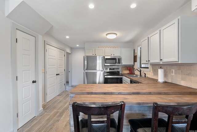 kitchen featuring appliances with stainless steel finishes, wood finish floors, a sink, and backsplash