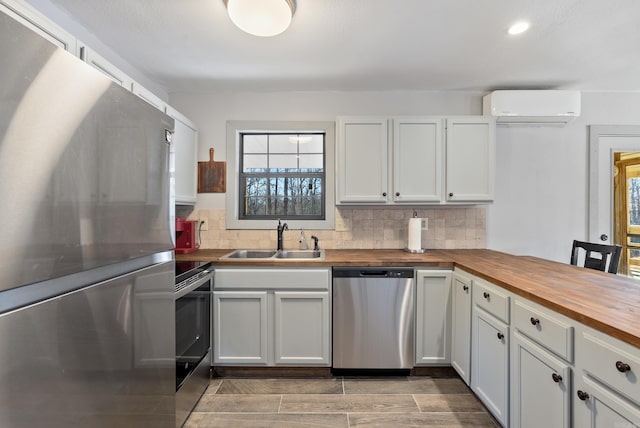 kitchen featuring decorative backsplash, appliances with stainless steel finishes, a sink, butcher block countertops, and a wall mounted air conditioner