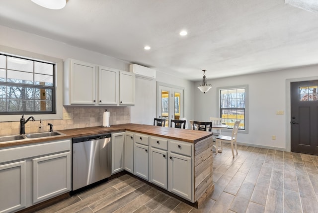 kitchen featuring dishwasher, wood counters, a peninsula, a sink, and a wall mounted AC