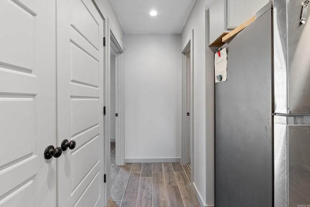 hallway with wood finish floors, baseboards, and recessed lighting