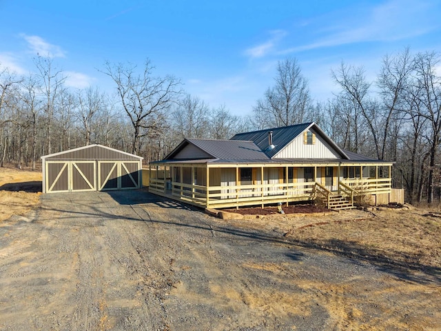 view of front of property featuring driveway, metal roof, a porch, and an outbuilding