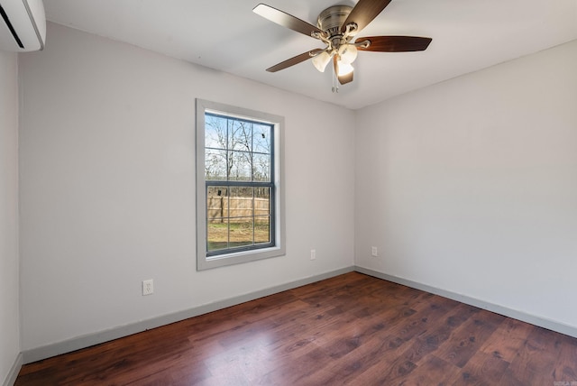 spare room featuring a wall mounted air conditioner, ceiling fan, baseboards, and wood finished floors