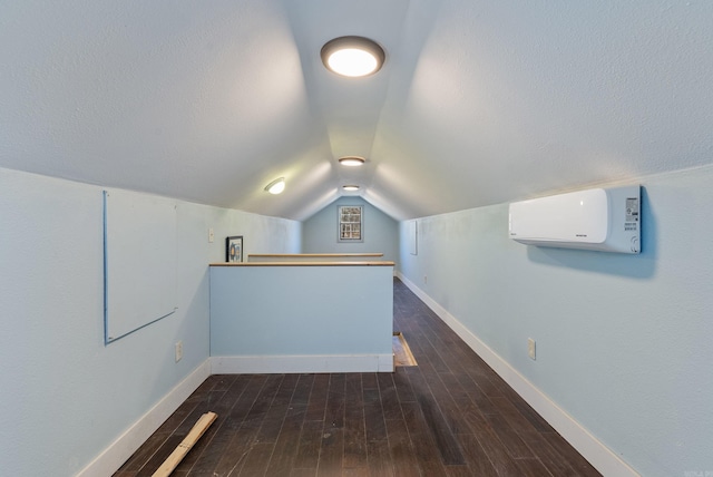 bonus room with lofted ceiling, an AC wall unit, dark wood-type flooring, and baseboards