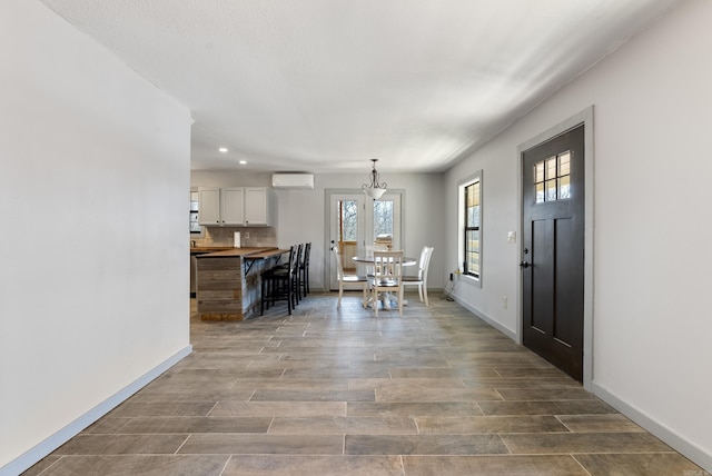 foyer featuring recessed lighting, baseboards, an AC wall unit, and wood finished floors