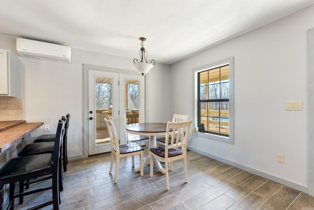 dining room featuring baseboards, wood finish floors, and a wall mounted air conditioner