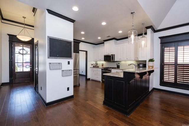 kitchen featuring a peninsula, light stone countertops, stainless steel appliances, and crown molding