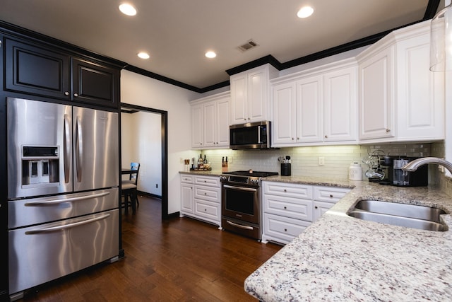 kitchen with dark wood-style flooring, tasteful backsplash, visible vents, appliances with stainless steel finishes, and a sink