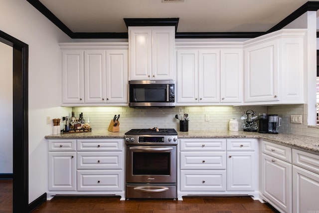 kitchen with appliances with stainless steel finishes, white cabinets, and tasteful backsplash