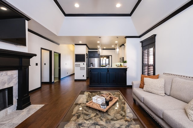 living room featuring ornamental molding, dark wood-type flooring, a fireplace, and baseboards