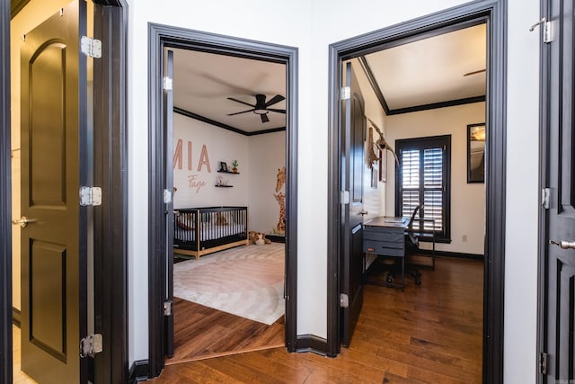 hallway featuring baseboards, wood finished floors, and crown molding