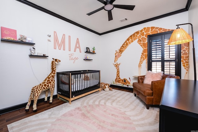 bedroom featuring crown molding, visible vents, ceiling fan, wood finished floors, and a crib