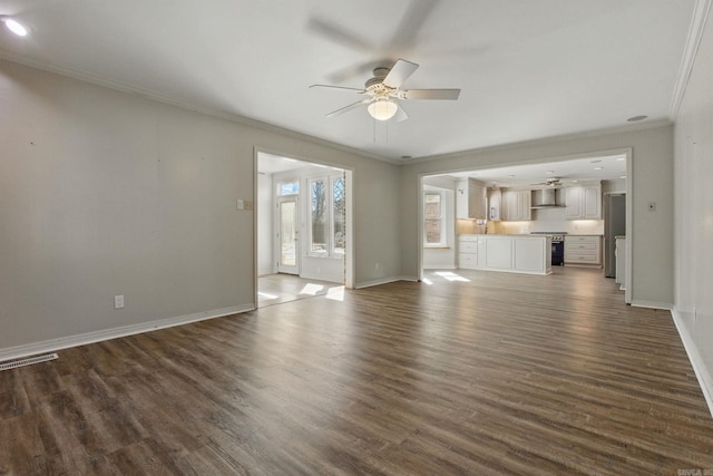 unfurnished living room with ceiling fan, ornamental molding, and dark wood finished floors