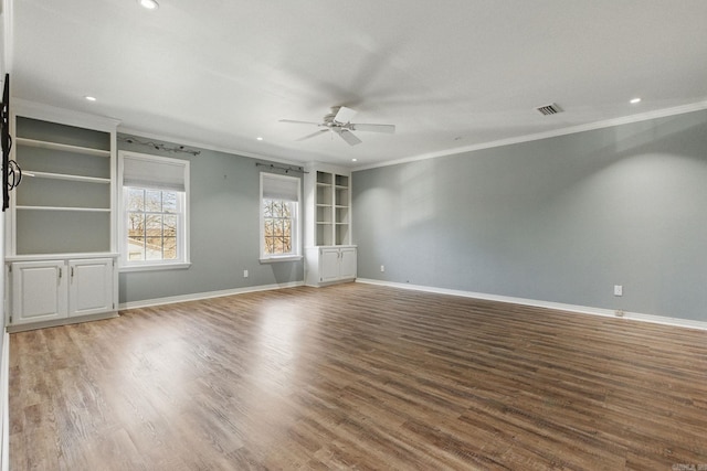 empty room with visible vents, ornamental molding, ceiling fan, wood finished floors, and baseboards