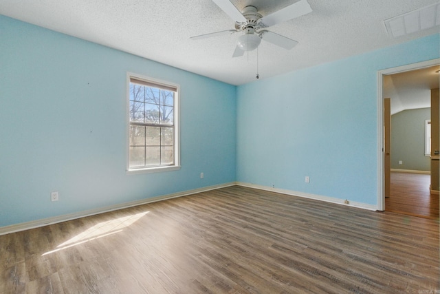 spare room featuring visible vents, a ceiling fan, a textured ceiling, wood finished floors, and baseboards