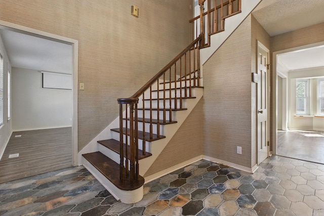 stairs with stone finish flooring, baseboards, and wallpapered walls